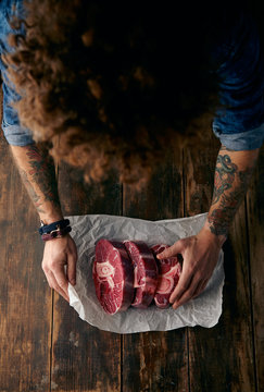Very top view curly head butcher packing three steaks in paper