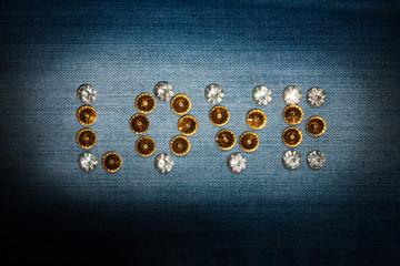 Word love made of rhinestones on denim fabric