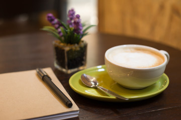Hot latte art coffee cup on wooden table and note book