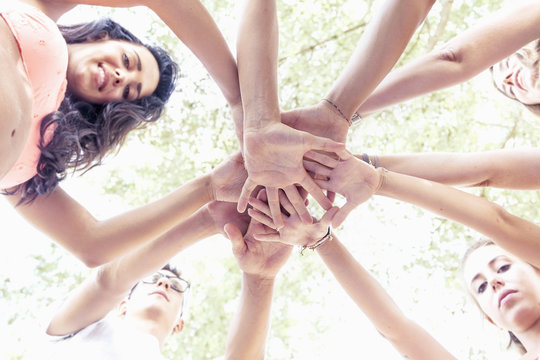 group of young adult putting their hands together in circle