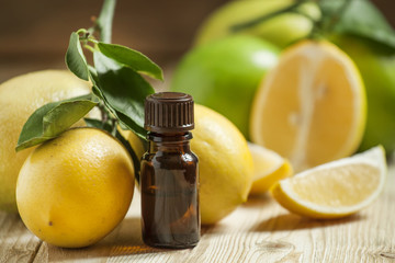 Essential oil of lemon and fresh lemons on the old wooden backgr
