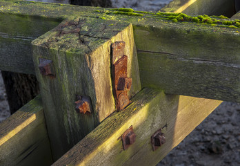 Details of wooden joints of old wooden jetty, showing rusty knuts and bolts.