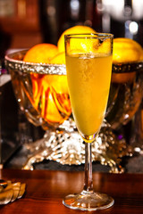 Champagne in a misted glass against the background of a vase with oranges