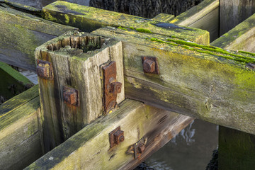 Details of wooden joints of old wooden jetty, showing rusty knuts and bolts.
