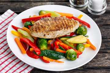 Grilled chicken fillet, breast with cooked vegetable  on plates.