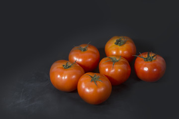 6 ripe red tomatoes on black background