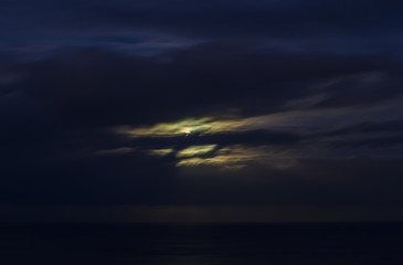 Fototapeta na wymiar Moon shining in cloudy night sky.