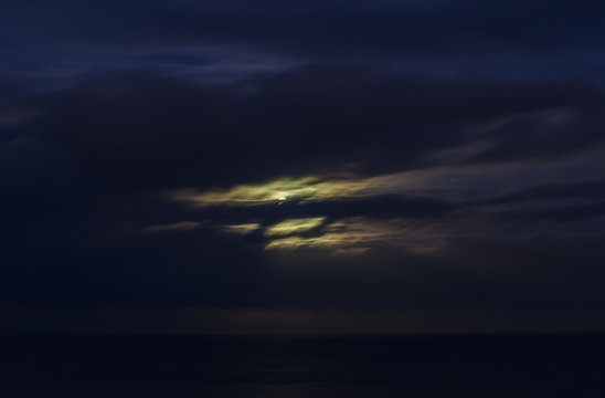 Moon shining in cloudy night sky.