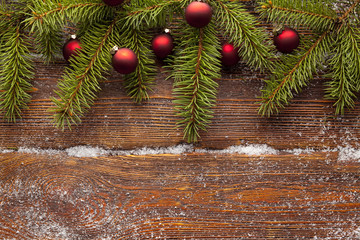 Branch of Christmas tree and baubles on wooden background