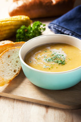corn soup with sliced bread on wooden board