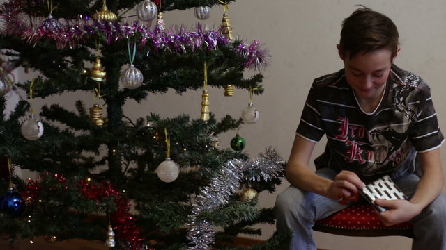 Teen Opening Christmas Gift Near Christmas Tree