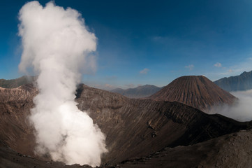 Volcano Bromo Errupting Smoke and sulfur under blue sky