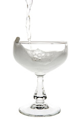 Liquid champagne poured into empty glass on white background. Clipping path incl.