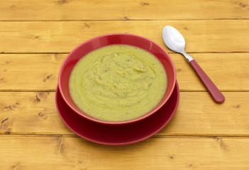 Full bowl of green soup with a spoon