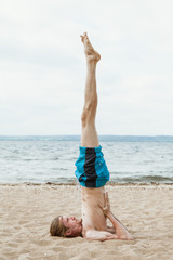 Adult man practices yoga on the beach