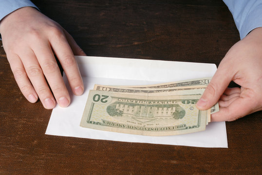 Pair of male caucasian hand holding USA dollars and white envelo