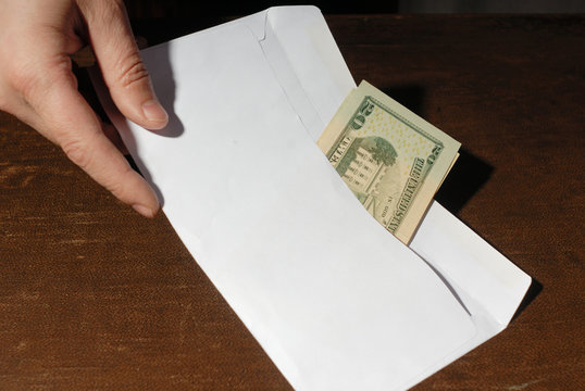 Male hand holding white envelome with money
