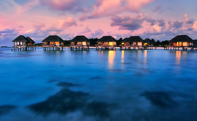 Water bungalows with beautiful twilight sky and sea in Maldives. Long Exposure.