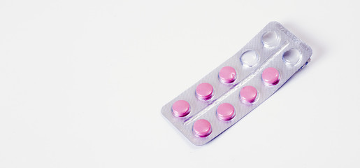 Pink medical pills on white table