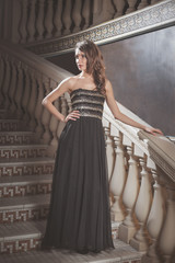 beautiful elegant woman in a black dress is standing on the steps of the vintage at the castle