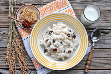 Rice cereal with raisins , honey, milk on wooden table 
