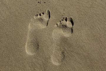 two left feet steps in sandy beach