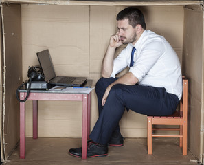 depressed businessman in a cardboard office