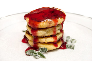 Cheese pancakes drenched with jam on the plate isolated on a whi