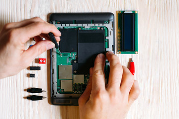 Technician repair tablet computer on wooden background