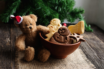 Christmas sugar cookies lies in a bowl, a teddy bear holding a cookie