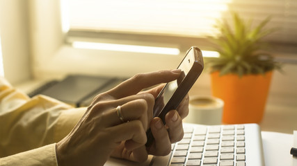 Woman's fingers buy online with smartphone at home with a computer.
