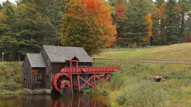 Pan of an old grist mill near Guildhall, Vermont with brilliant Fall foliage in the background.
