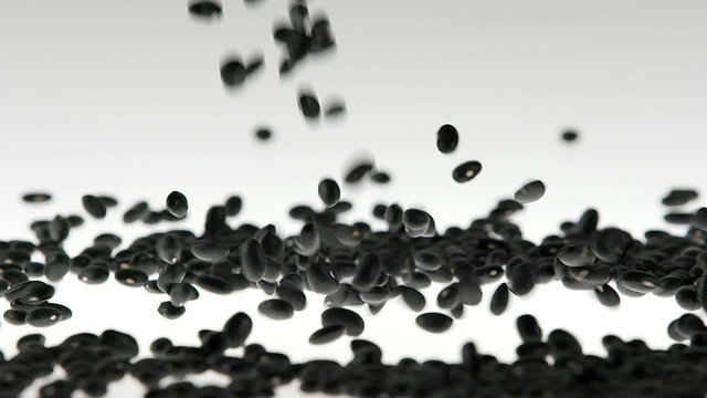 Super Slow Motion Black Soy Beans Falling on White Surface