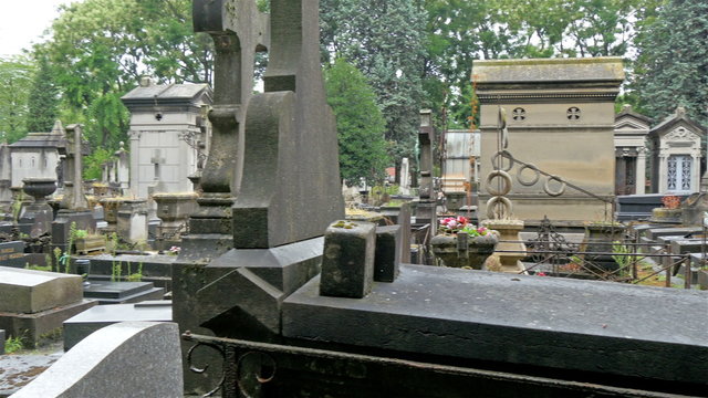 Lots of tombstones in a cemetery in Paris. Some of the tombs have withered leavs and moss on it already