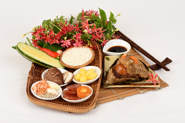 Zongzi and ingredients Ginkgo Biloba, shrimp, mushrooms, onion, garlic, duck egg, sticky rice, sausage, sauce and pepper, pork, deep fried combination wrapped in bamboo leaves and then steamed.