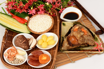 Fototapeta na wymiar Zongzi and ingredients Ginkgo Biloba, shrimp, mushrooms, onion, garlic, duck egg, sticky rice, sausage, sauce and pepper, pork, deep fried combination wrapped in bamboo leaves and then steamed.