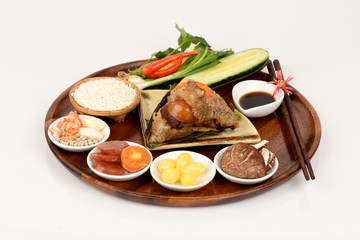 Zongzi and ingredients Ginkgo Biloba, shrimp, mushrooms, onion, garlic, duck egg, sticky rice, sausage, sauce and pepper, pork, deep fried combination wrapped in bamboo leaves and then steamed.