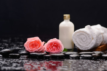 Fototapeta na wymiar Two rose and towel with massage oil and therapy stones 