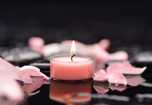 Beautiful rose petals with candle and therapy stones 