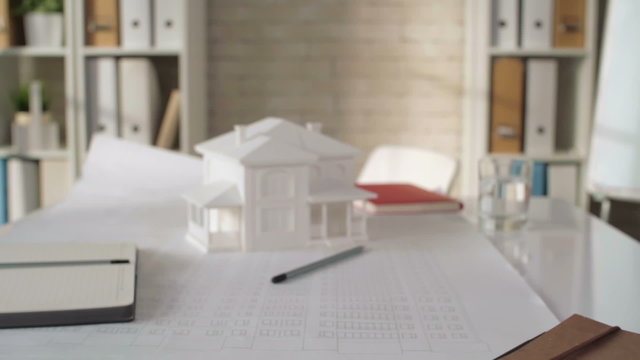Zoom out of paper house model and sketch on the office table