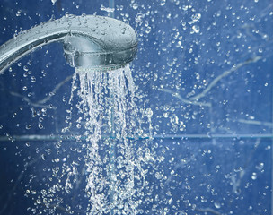 Naklejka na ściany i meble Shower on blue background with water drops fly in the air, image with space for text on the right