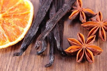 Obraz na płótnie Canvas Star anise, fragrant vanilla and dried orange on wooden surface