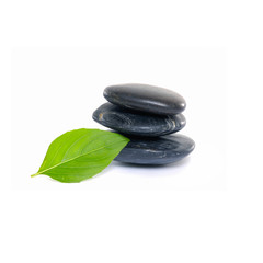 Stacked black stones with single green leaf 