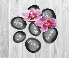 Obraz na płótnie Canvas Black spa stones and orchid flowers on wooden background