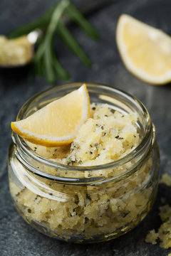 Body scrub of sea salt with lemon, rosemary and olive oil in glass jar on stone table, homemade cosmetic for Spa care