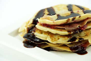 Fresh homemade crepes on plate with chocolate and strawberry jam