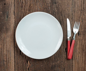 Hand hold fork and knife with plate on wood