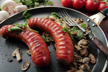 Fresh grilled sausages with mushrooms on a hot pan