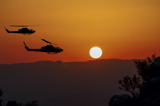 Two flying army helicopters on sunset background