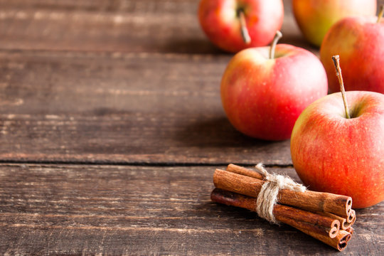 fresh apples and cinnamon on a wooden table